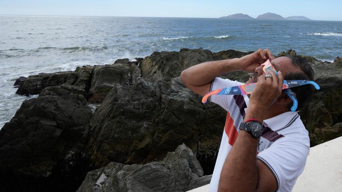 Un hombre prueba unas gafas especiales para mirar directamente al sol y poder ver el eclipse de hoy, en Mazatlan (México).