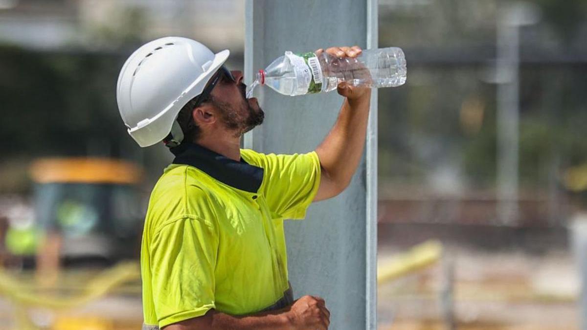 Un treballador de la construcció beu aigua per combatre la calor.