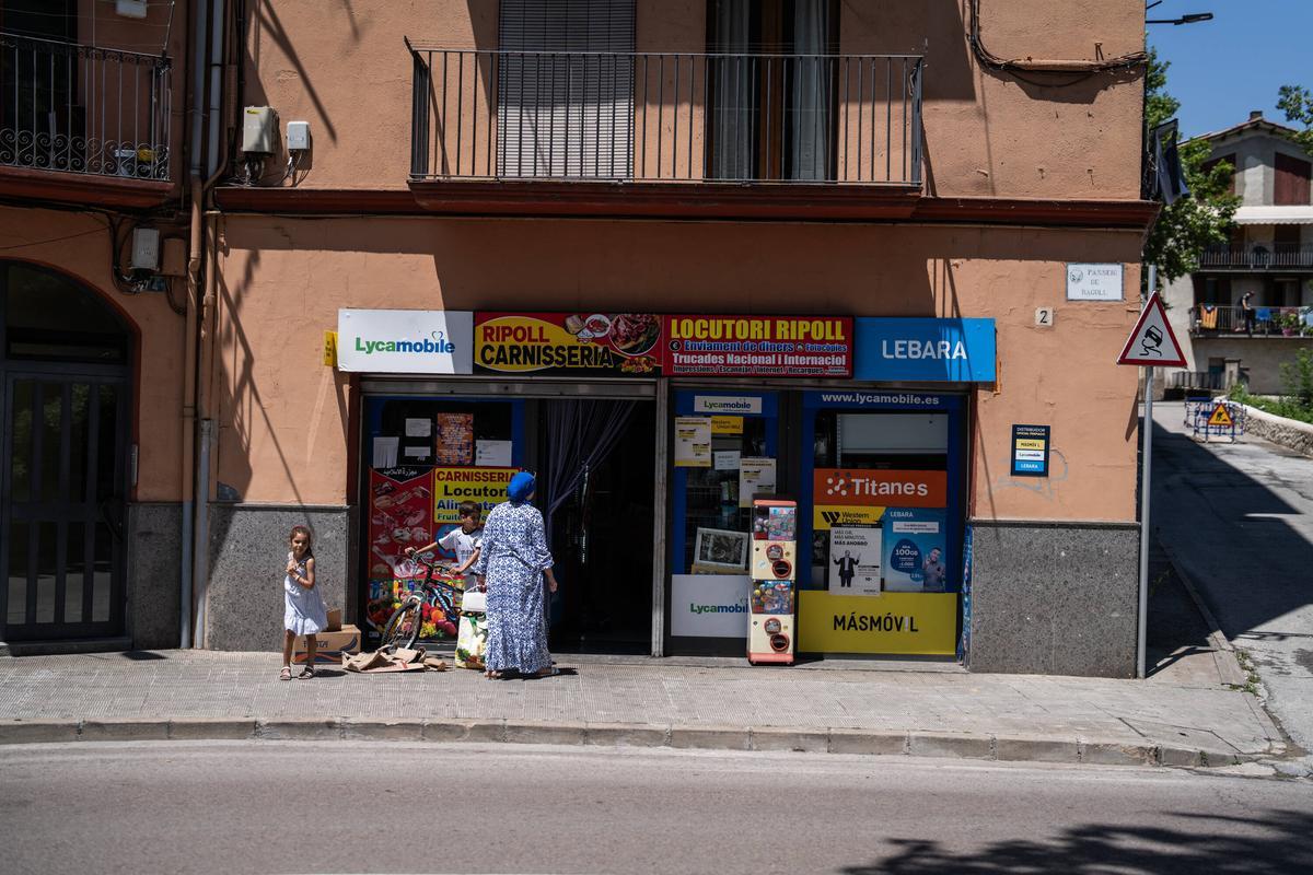 Halima et ses deux enfants, devant le salon qu'elle dirige avec son mari à Ripoll.