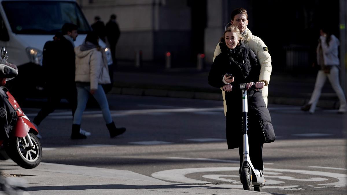 Dos jóvenes circulan en patinete eléctrico por el centro de Madrid