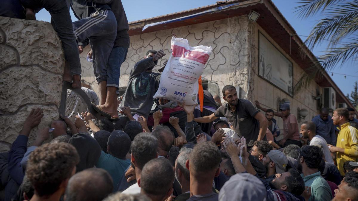 Habitantes del centro de Gaza reciben sacos de harina de la UNRWA en Deri al Balah.