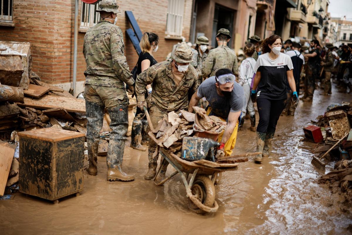 La photographie vue à droite du roi. Des militaires, des voisins et des volontaires enlèvent la boue des rues de Paiporta neuf jours après les dégâts.