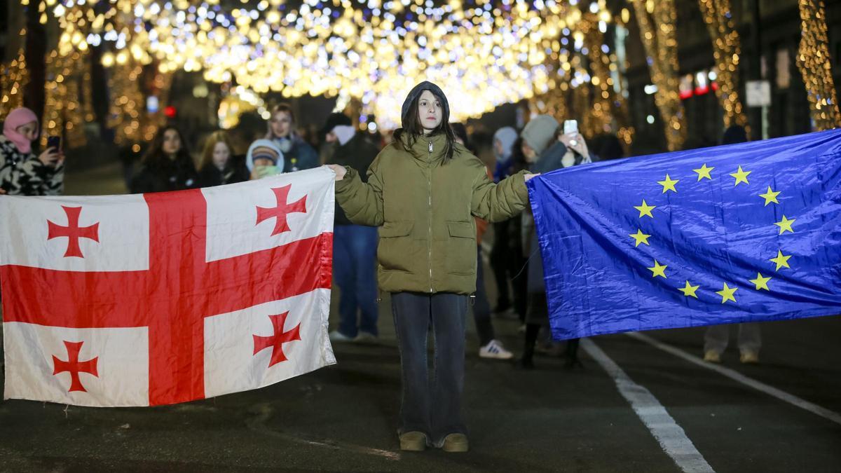 Una manifestante sostiene una bandera de Georgia y otra de la UE durante una manifestación en Tblisi el pasado 22 de diciembre.