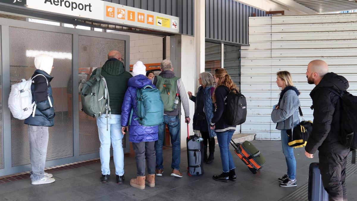 Un grupo de viajeros ante la puerta cerrada de la estación de Rodalies del aeropuerto de El Prat.