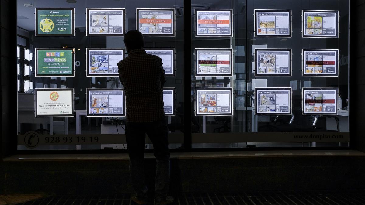 Un hombre mira en el escaparate de una inmobiliaria las ofertas de pisos y casas en venta y alquiler.