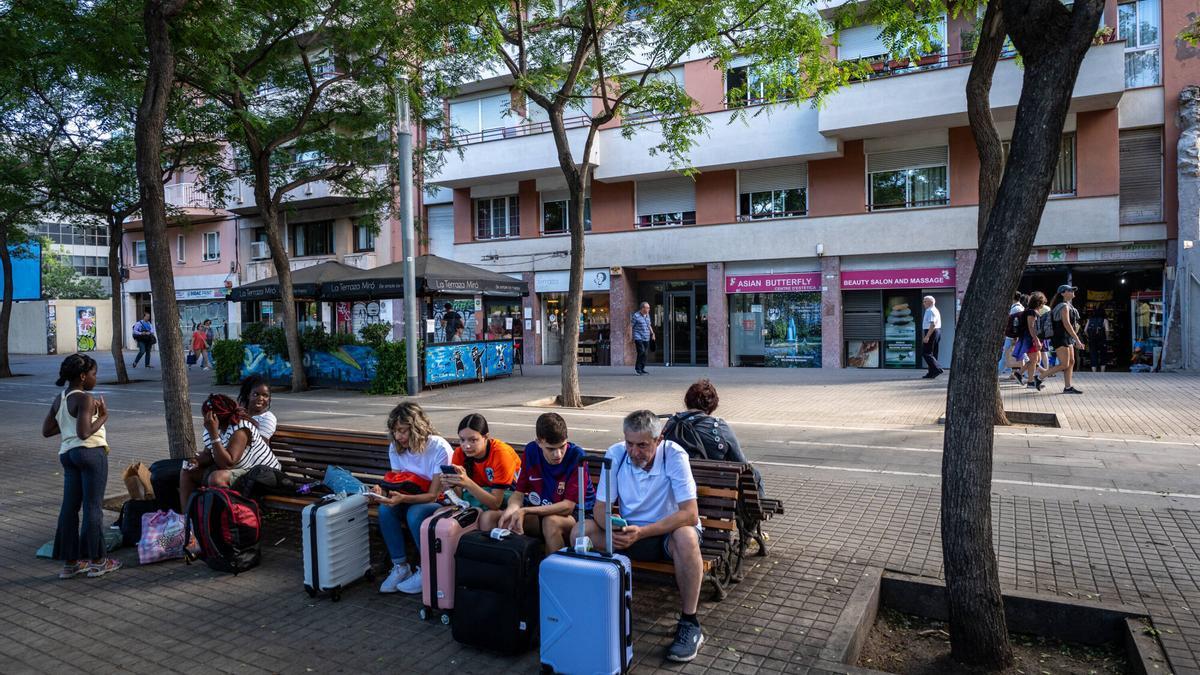 Turistas esperando con sus maletas delante de un bloque de pisos turísticos en la calle de Tarragona, en Barcelona.