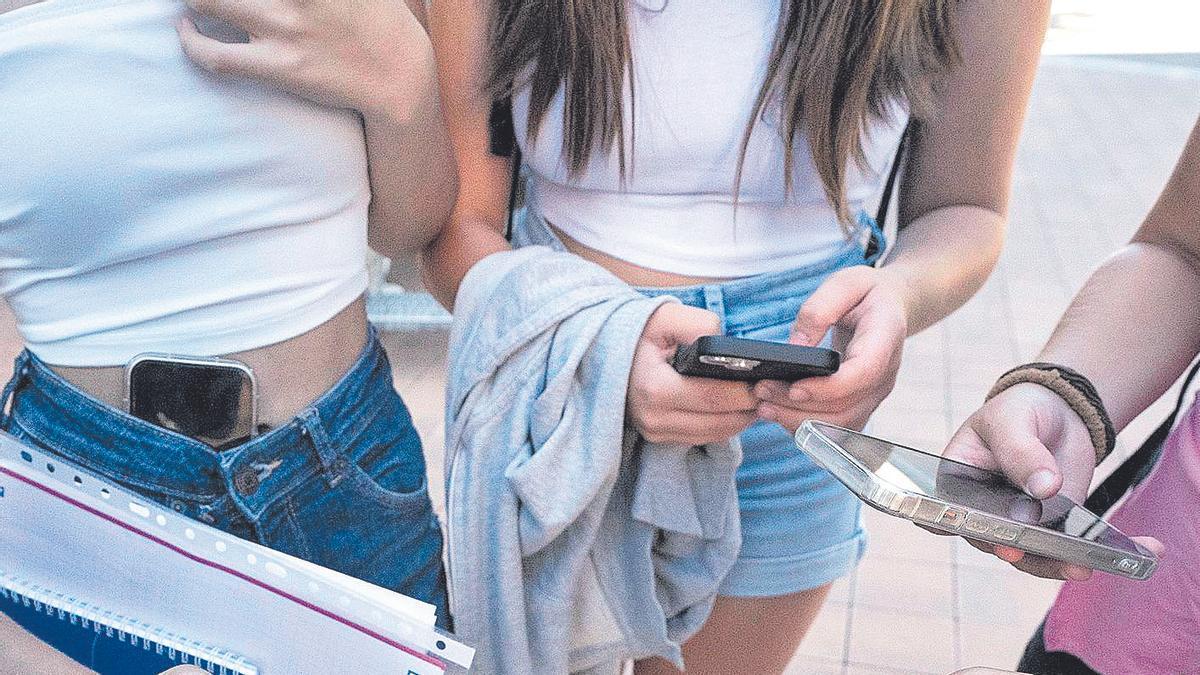 Un grupo de adolescentes consulta sus móviles.