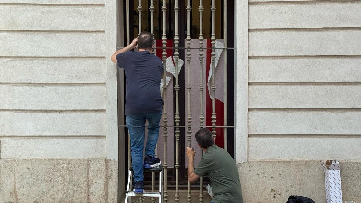 Operarios de las Corts cubren las ventanas de despachos de Compromís donde colgaban carteles pidiendo la dimisión de Mazón.