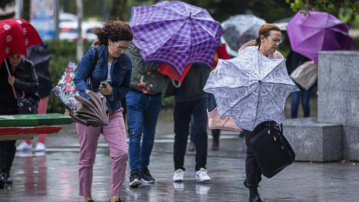 Varias personas se protegen de la lluvia en Valencia.