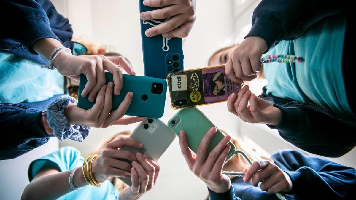 Un grupo de jóvenes, con sus móviles en un centro educativo.
