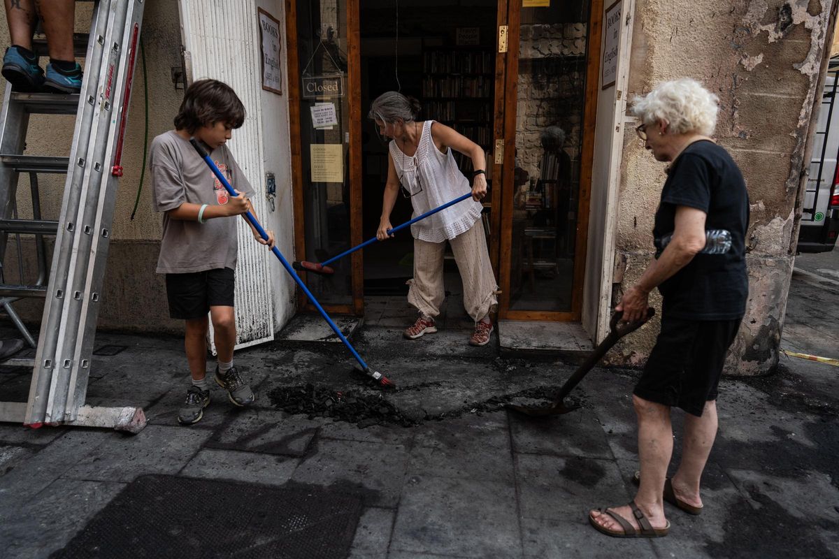 Feu dans la rue Verdi, l'une des routes décorées par les festivals de Gràcia. Le propriétaire de la librairie Hibernan nettoie les restes de cendres.