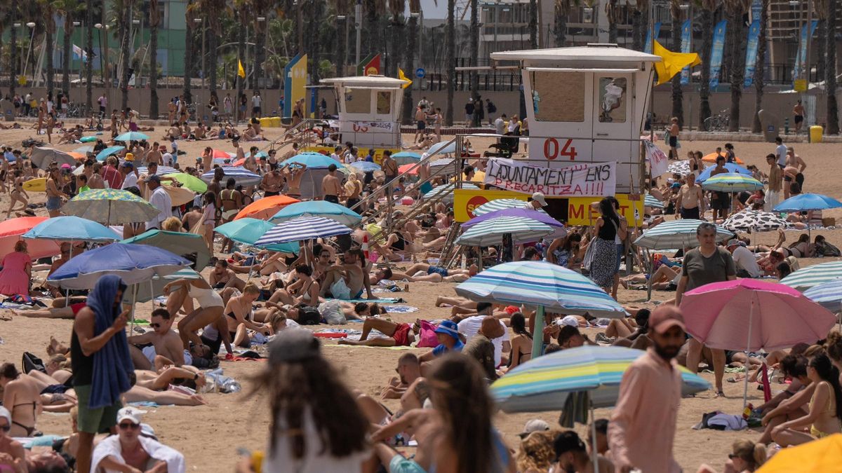 Bañistas, banderas amarillas y pancartas en los puestos de socorrismo este viernes en una playa de Barcelona.