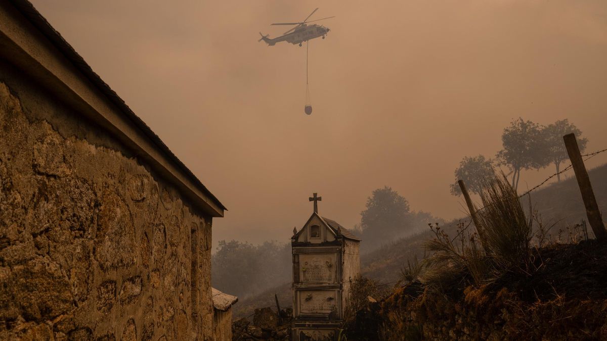Un helicóptero de control de incendios sobrevuela el cementerio la localidad de Vilar durante el incendio forestal en Chandrexa de Queixa (Ourense).