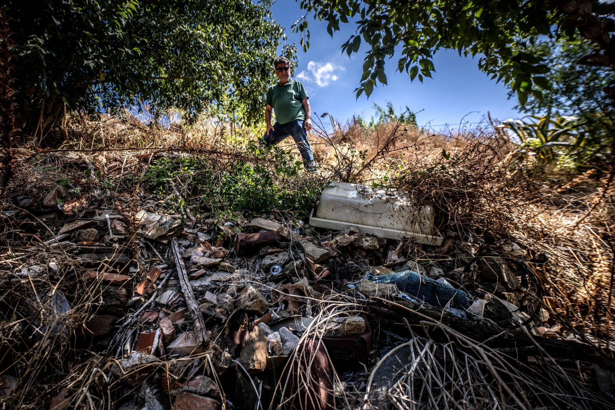 Lluís Jordà, miembro de la Associació d’Amics del Monestir de Sant Jeroni de la Vall d’Hebron, junto a escombros y basura en el terraplén que cubre parte de las ruinas del monasterio.