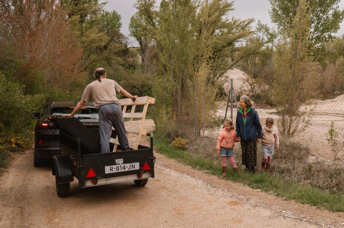 Maikee, à côté de ses deux filles, observe comment son mari Tibor, transporte des panneaux solaires de ramassage pour le projet Ecoaldea à Bárcena de Bureba.