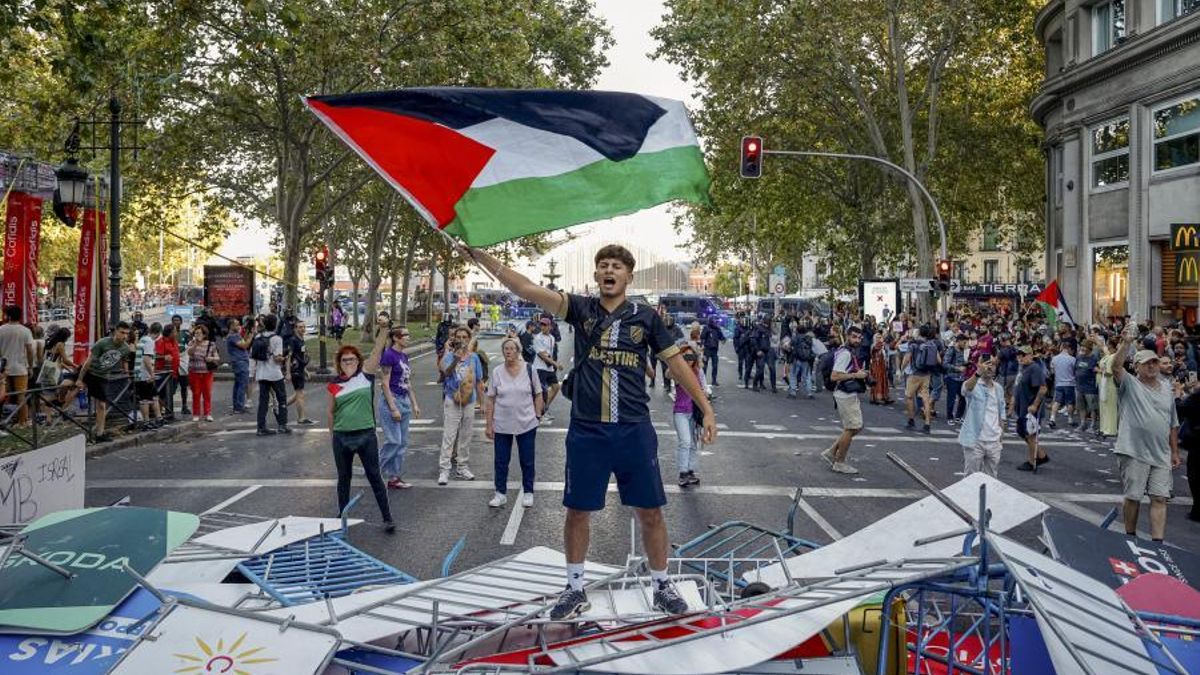 Un manifestante propalestino, sobre las vallas del recorrido de la Vuelta en el Paseo del Prado de Madrid.