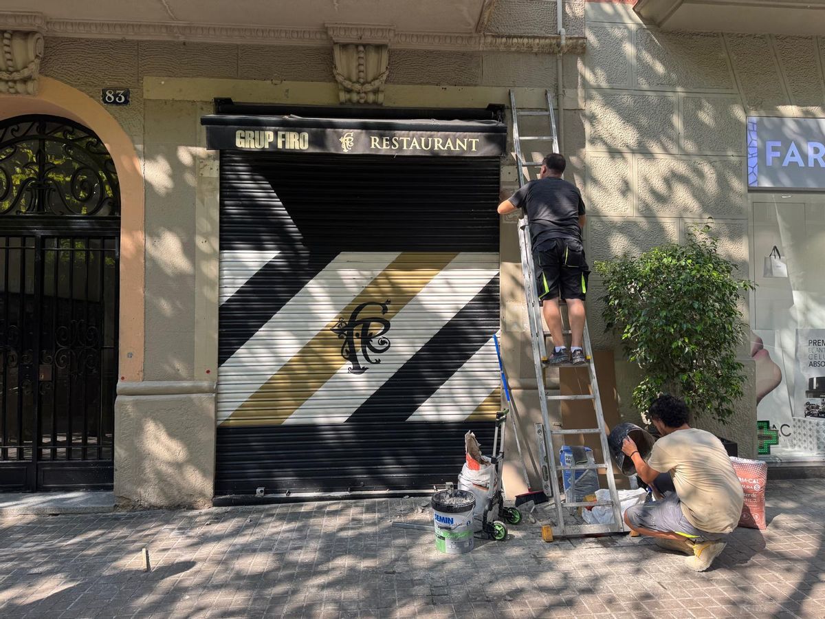 Deux travailleurs ont fini de retirer l'étiquette d'une entreprise qui ne conserve son nom que dans l'auvent.