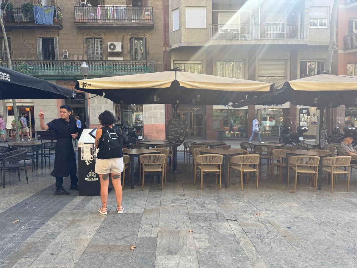 Un fonctionnaire municipal passe au nombre de tables de tables sur une terrasse dans la Avenda de Gaudí.