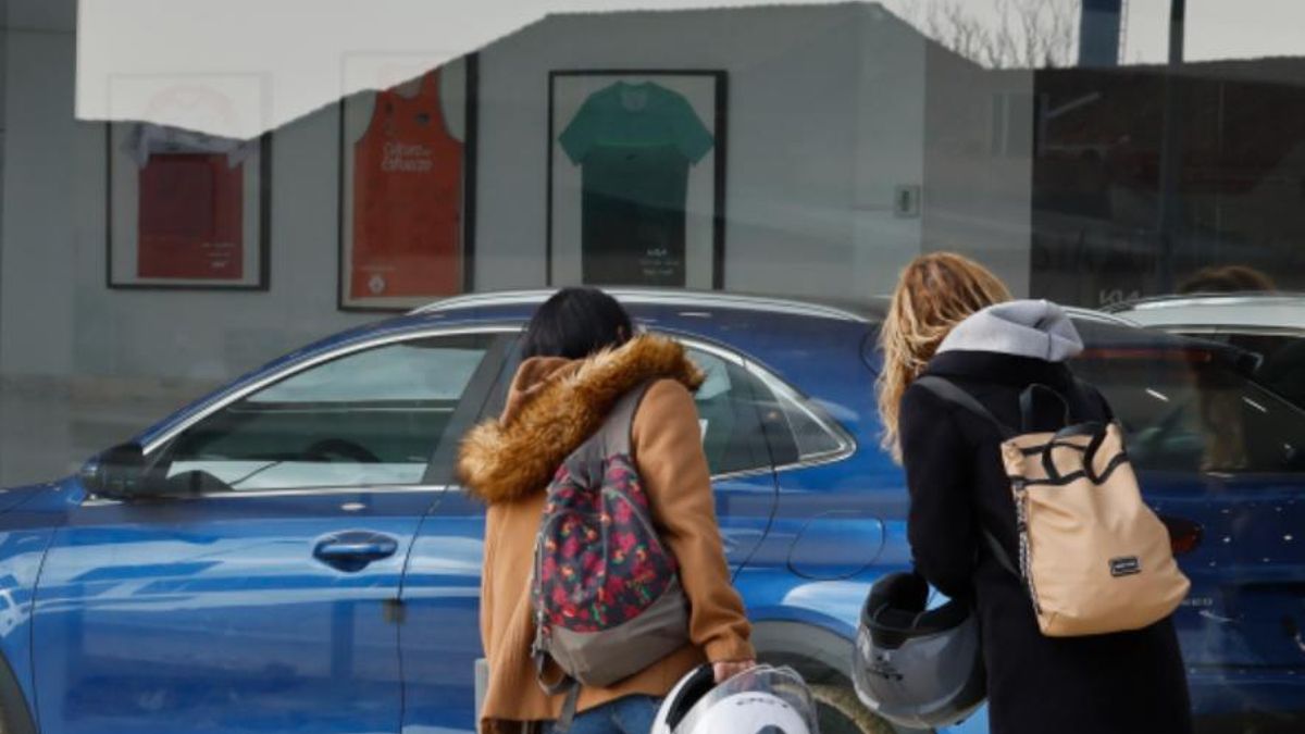 Dos mujeres miran coches en un concesionario.