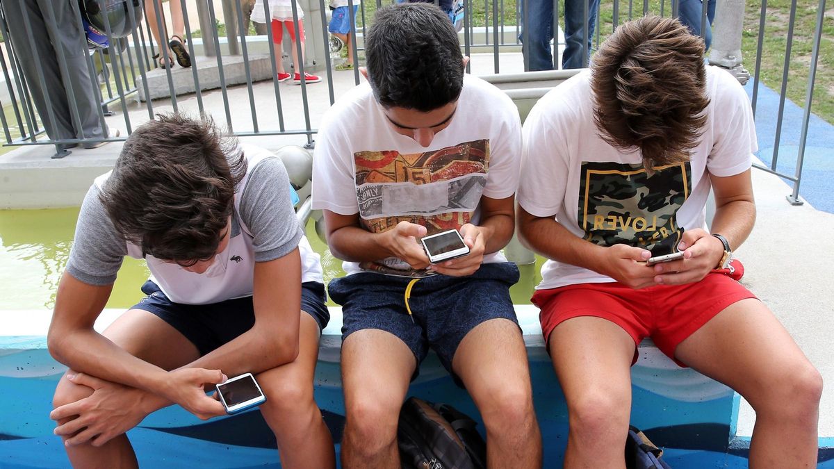 Un grupo de adolescentes juega con el móvil.