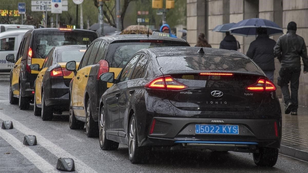 Taxis y un vehículo VTC, circulando juntos por el carril taxi, en Barcelona.