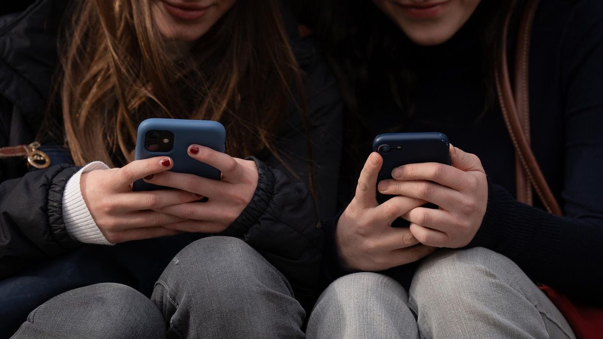Dos adolescentes usan sus teléfonos móviles
