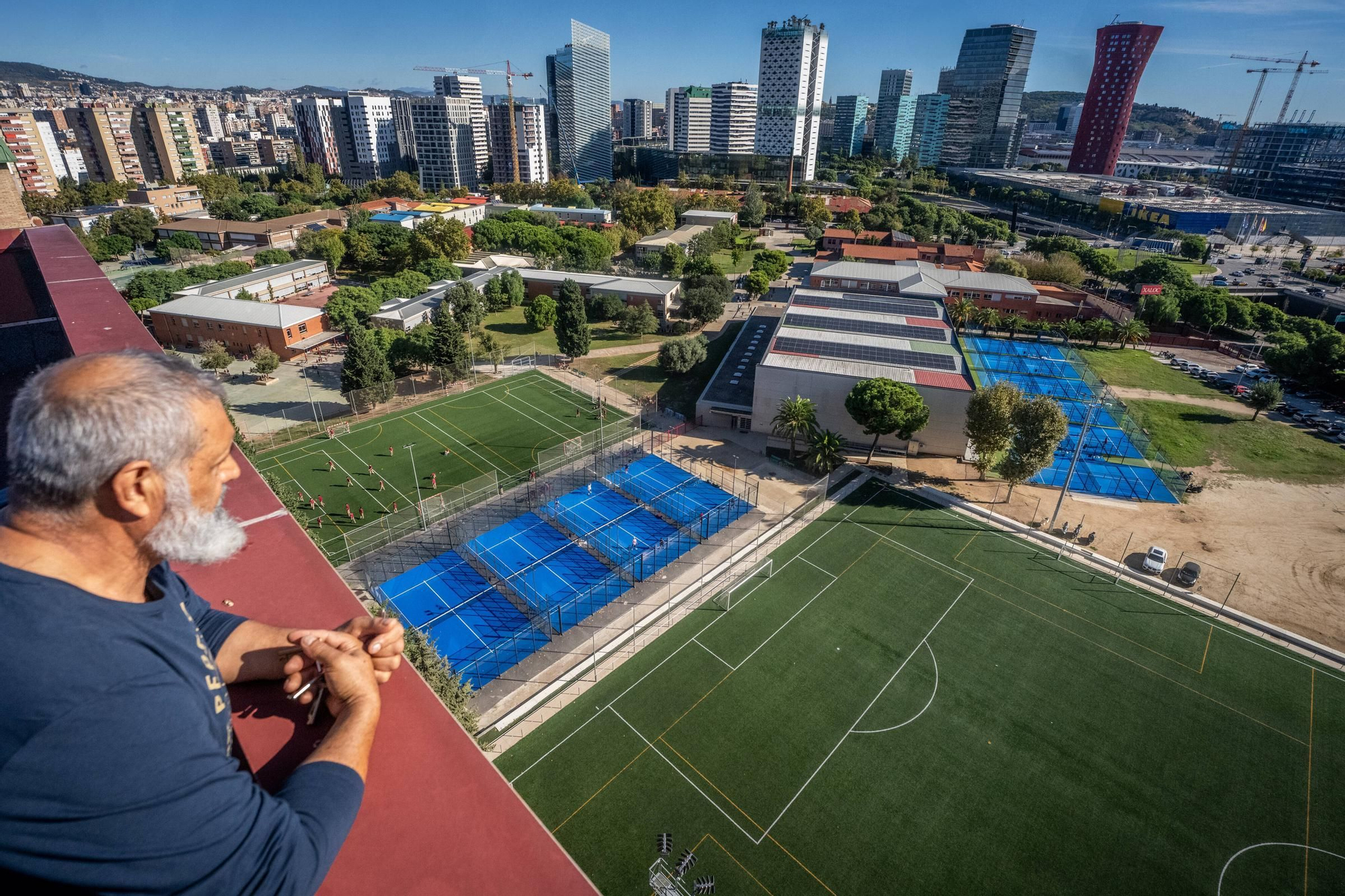 Un vecino del Gornal mira a las pistas deportivas del colegio Xaloc desde la azotea de su edificio.