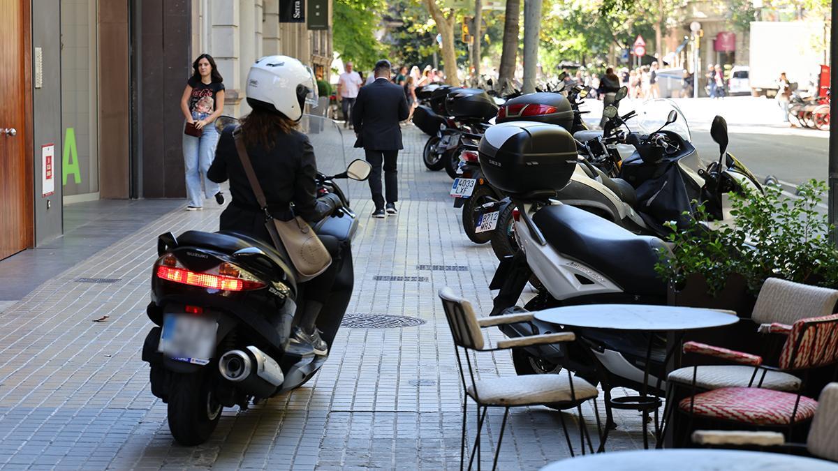 Una moto se dispone a aparcar en la acera, en la calle de Provença de Barcelona
