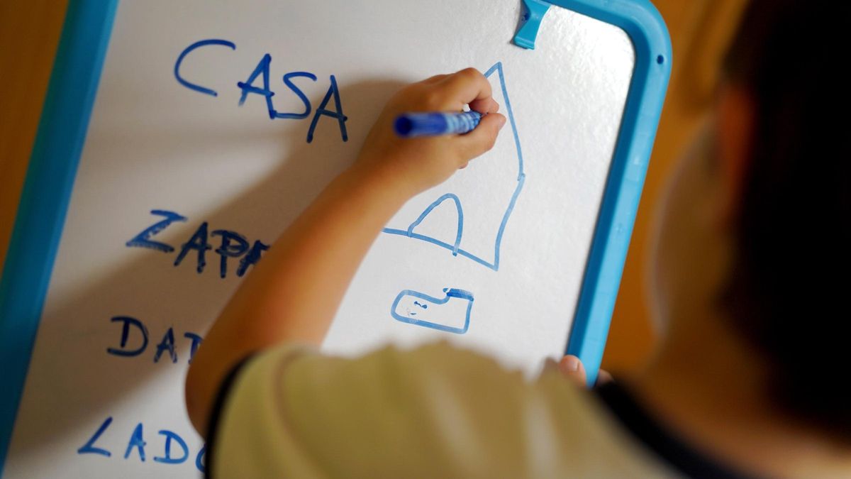 Un escolar escribe y dibuja en una pizarra.