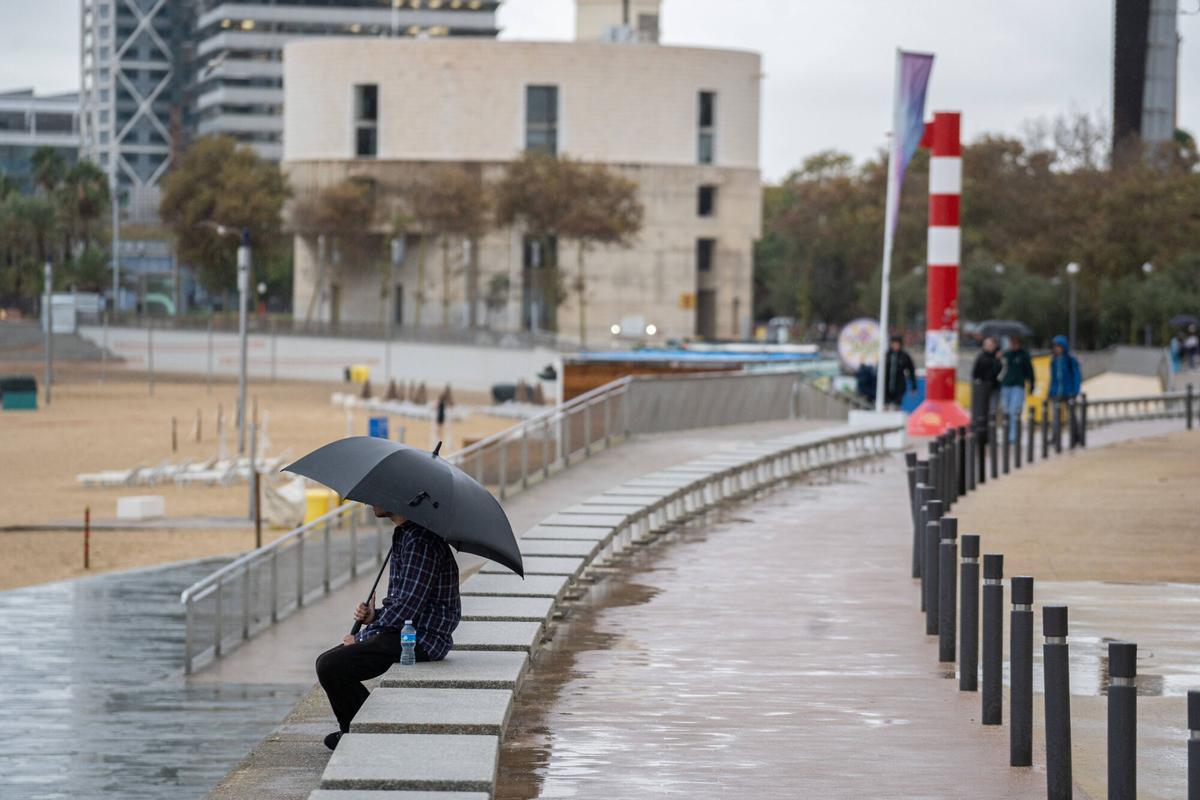 Personne assise avec un parapluie sous la pluie à Barcelone.