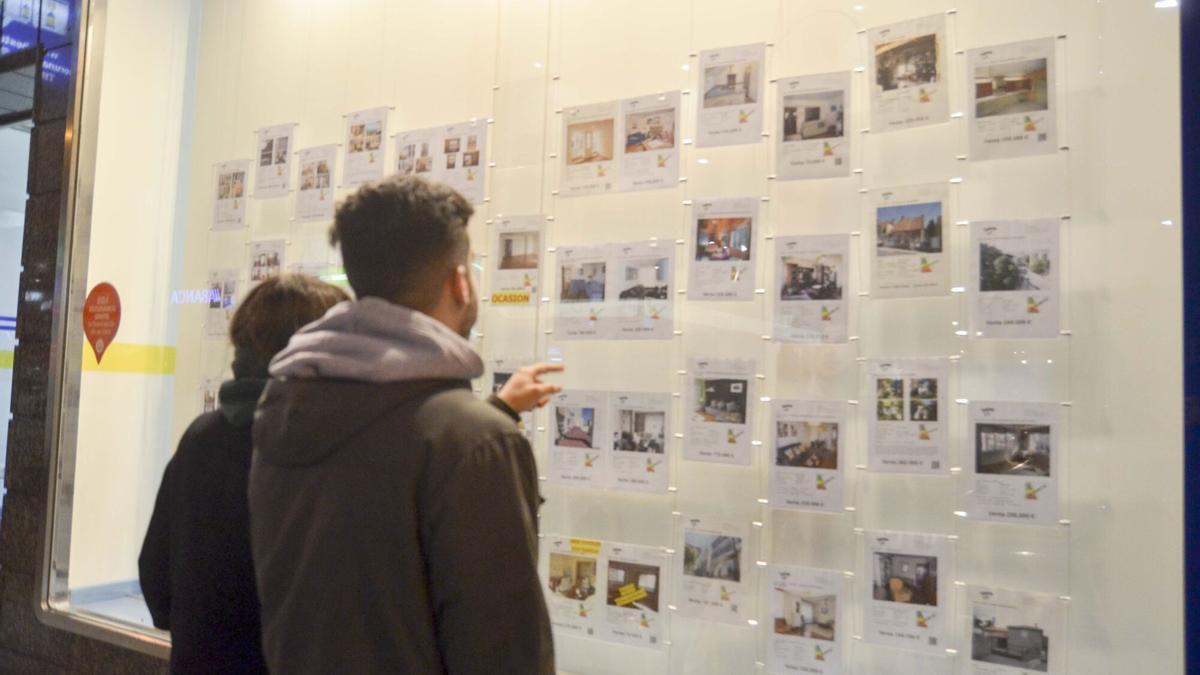 Dos jóvenes miran las ofertas de pisos en alquiler en una inmobiliaria de A Coruña.