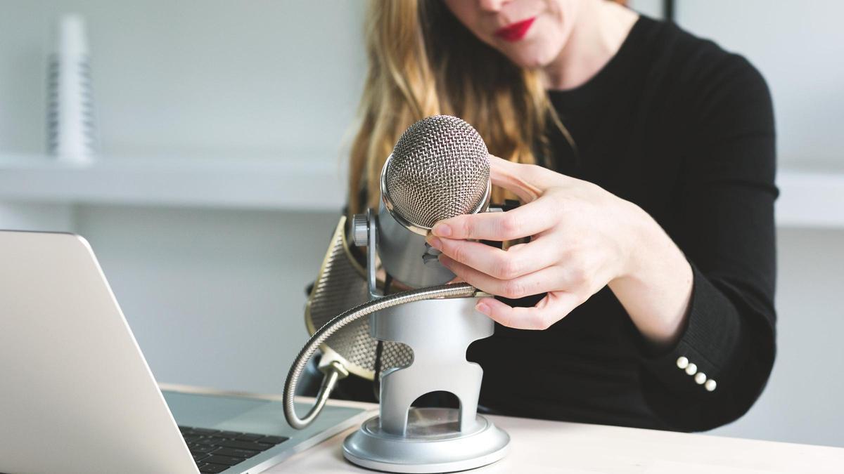 Una mujer ajusta un micrófono para grabarse.