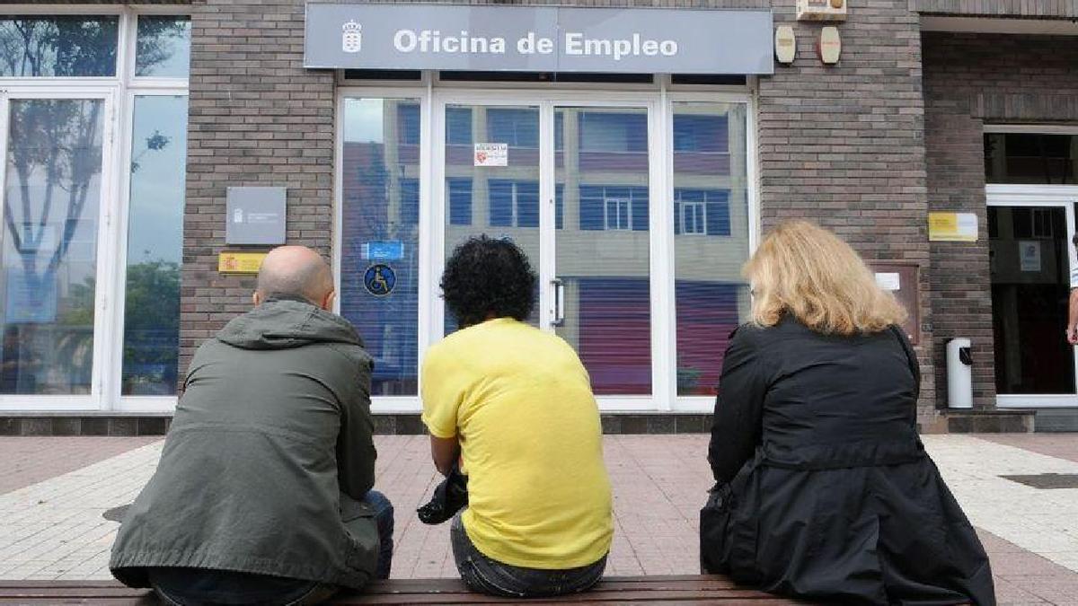 Trois personnes assises devant une agence pour l'emploi.