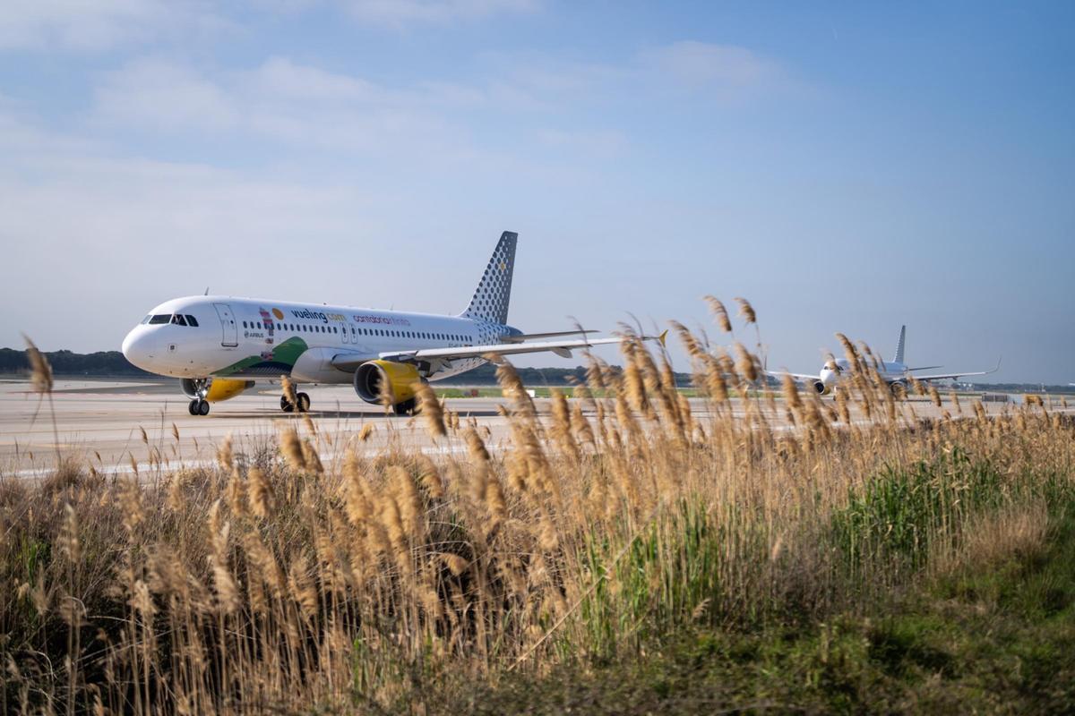 Un avion Vueling prend son tour sur la piste maritime de l'aéroport El Prat, prêt à décoller.