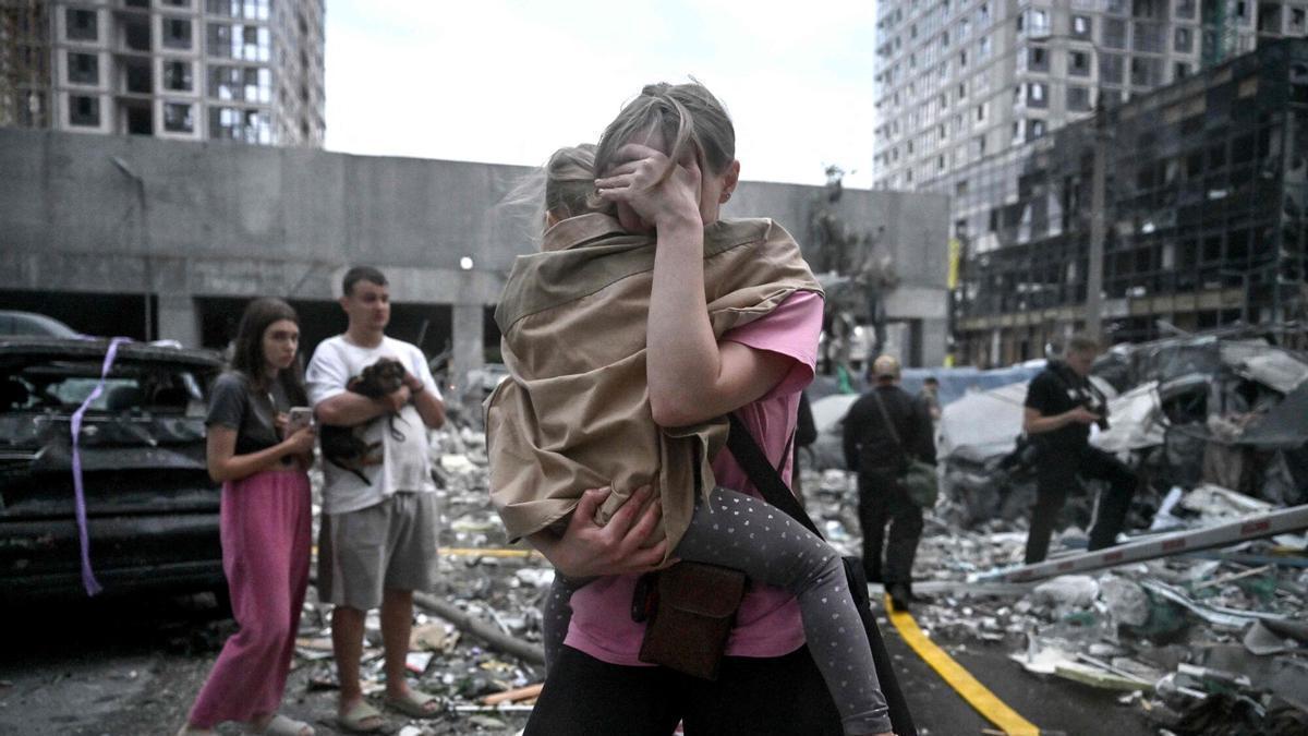 Una mujer, residente de un edificio residencial de varias plantas dañado, sostiene a su hija tras un ataque con misiles rusos en la capital ucraniana, Kiev, esta mañana.
