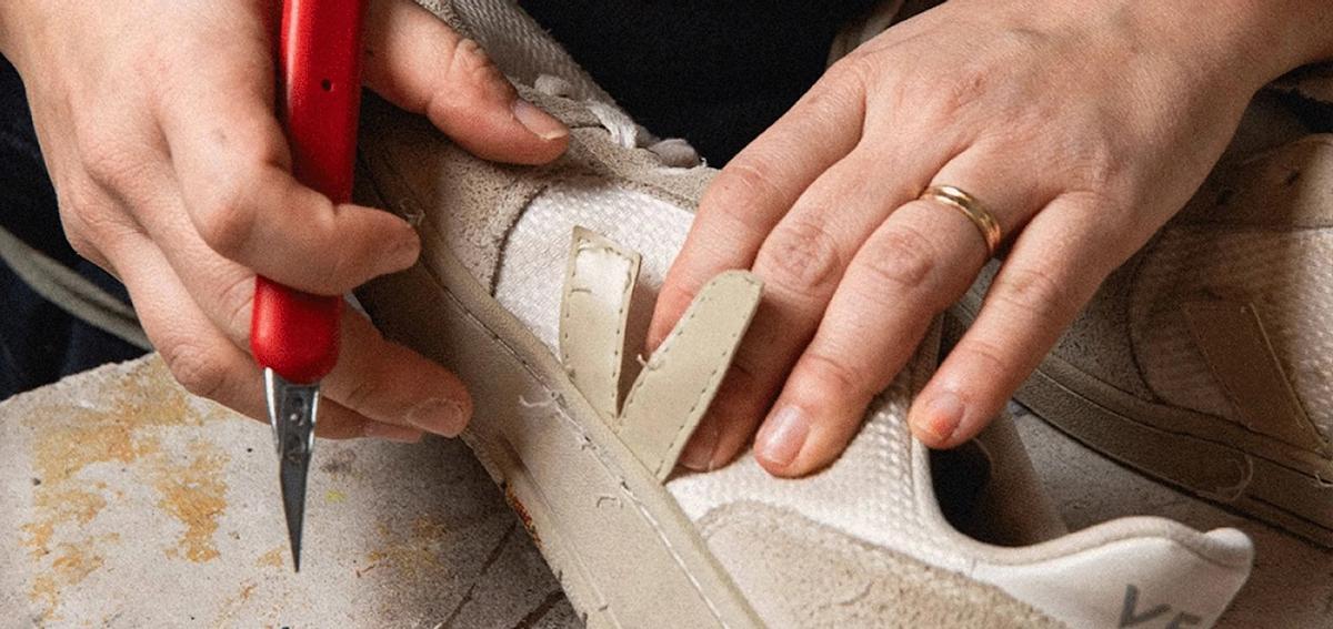 Un artisan répare une sneaker Veja.