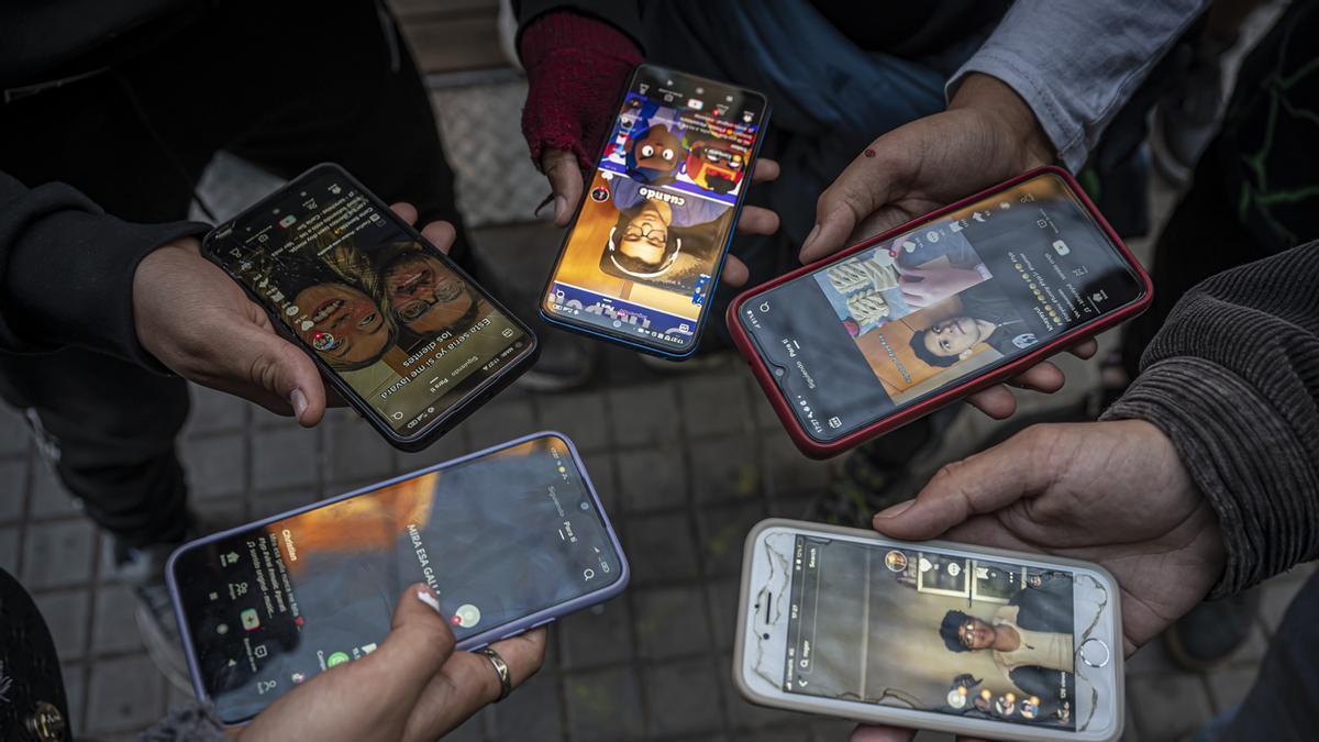 Varios jóvenes muestran sus móviles, con los que acceden a redes sociales.