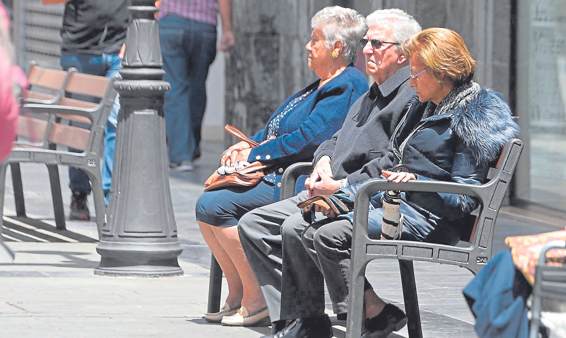 Varias personas mayores sentadas en un banco.