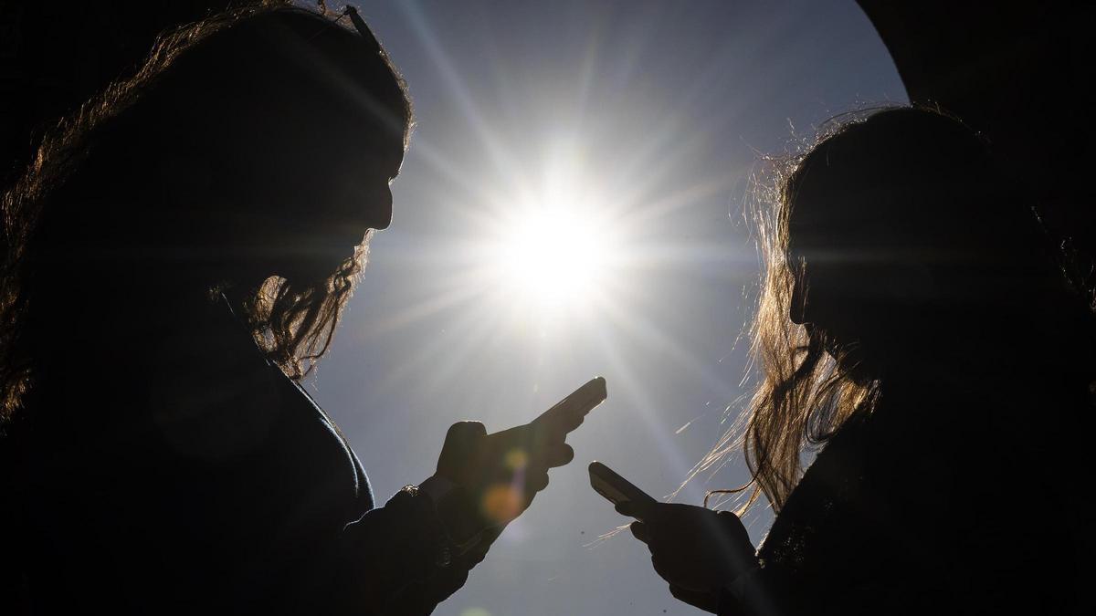 Dos adolescentes, con sus móviles.