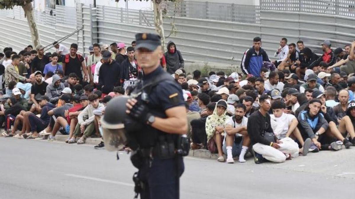 Un agente de la Policía Nacional, ante un grupo de migrantes en Ceuta.