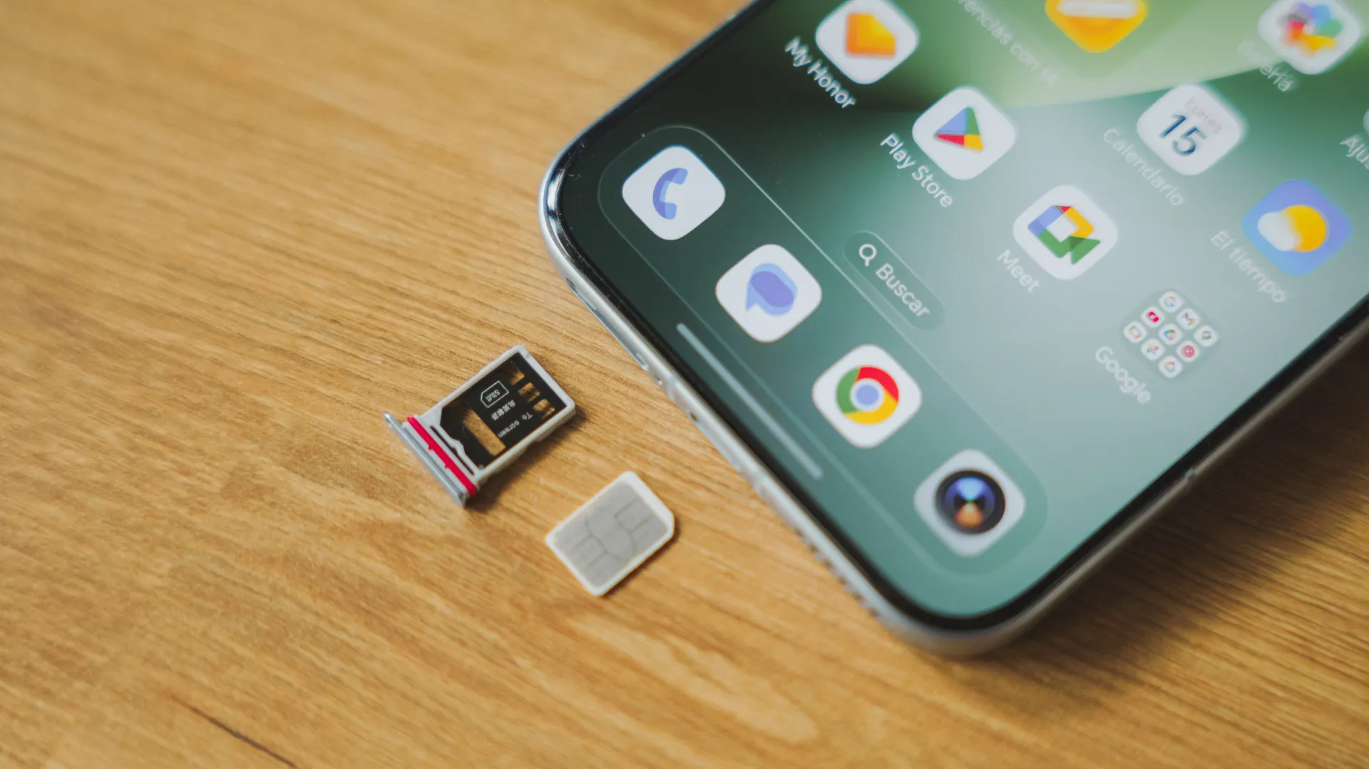 Plateau de carte nano-SIM extrait à côté du bord inférieur d'un téléphone Honor Magic8 Pro sur une table en bois.