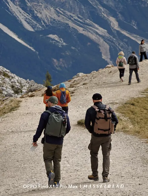 Randonneurs avec sacs à dos marchant sur un sentier de terre dans les montagnes.