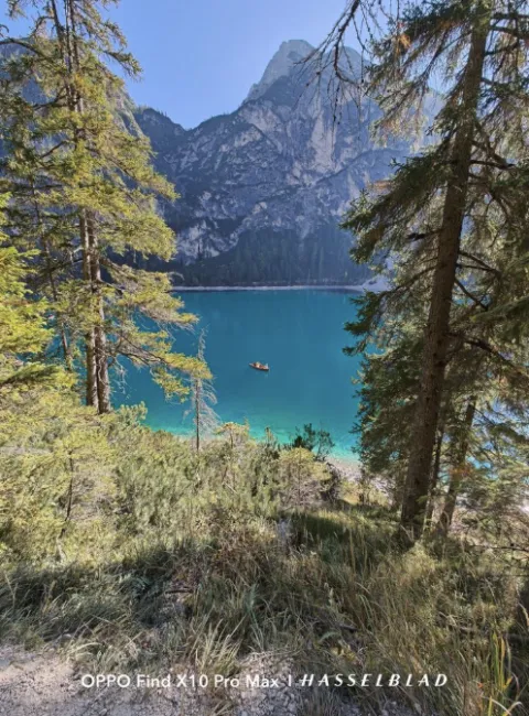 Chaloupe naviguant sur un lac aux eaux turquoise entouré de conifères et de grandes parois rocheuses.