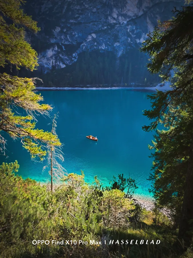 Plan général d'un lac aux eaux turquoise entre montagnes et arbres avec un petit bateau au centre.