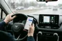 Conductor interactuando con un smartphone y la pantalla de Android Auto en el salpicadero de un coche.
