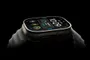 Vista lateral en ángulo de un Apple Watch con caja de titanio y correa deportiva sobre fondo negro.
